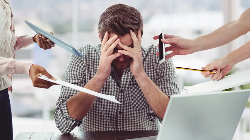 An image of a man being overwhelmed with people putting papers and phones near his head