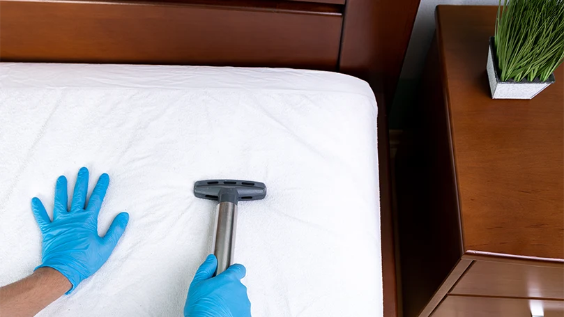 an image of cleaning a mattress topper with a vacuum cleaner