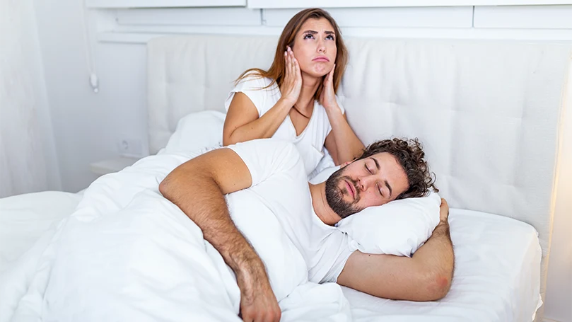 an image of a woman cannnot sleep due to man's snoring