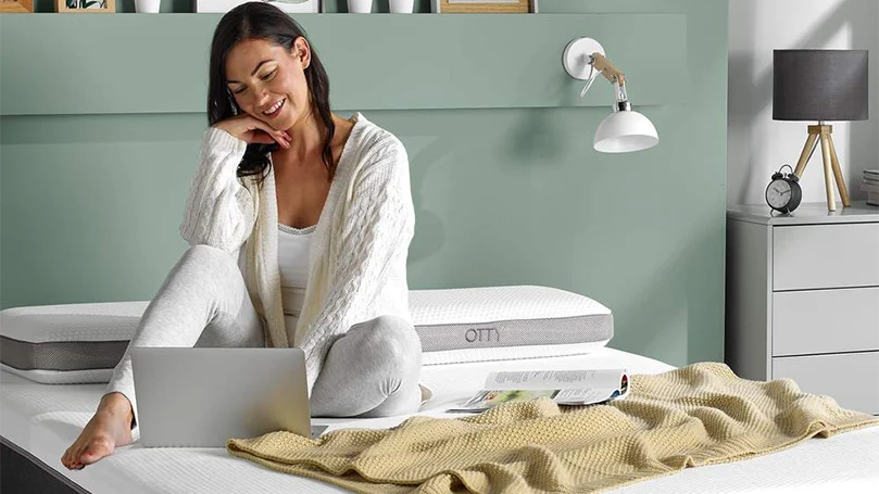 an image of a young woman sitting on OTTY Aura hybrid mattress