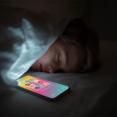 An image of a child sleeping next to a phone with the screen turned on