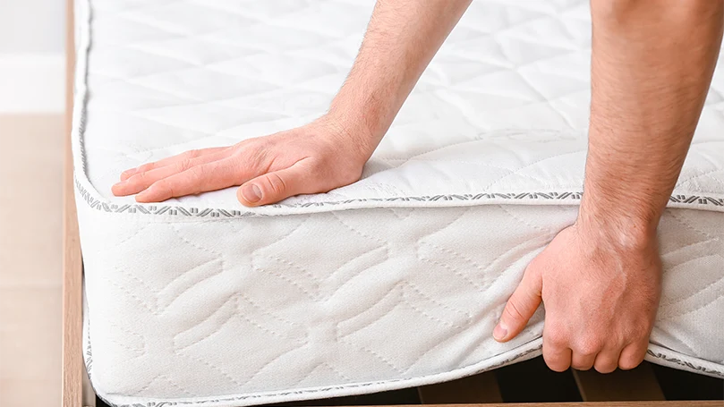 an image of a man lifting up a gel topped mattress