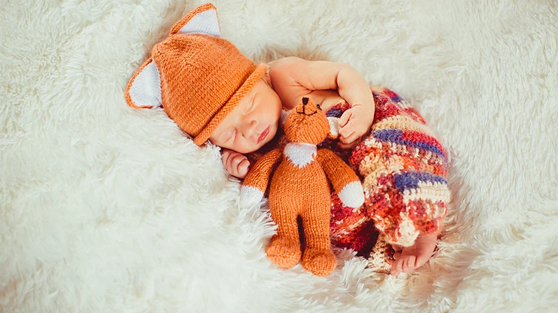 An image of a baby sleeping on its back in crib