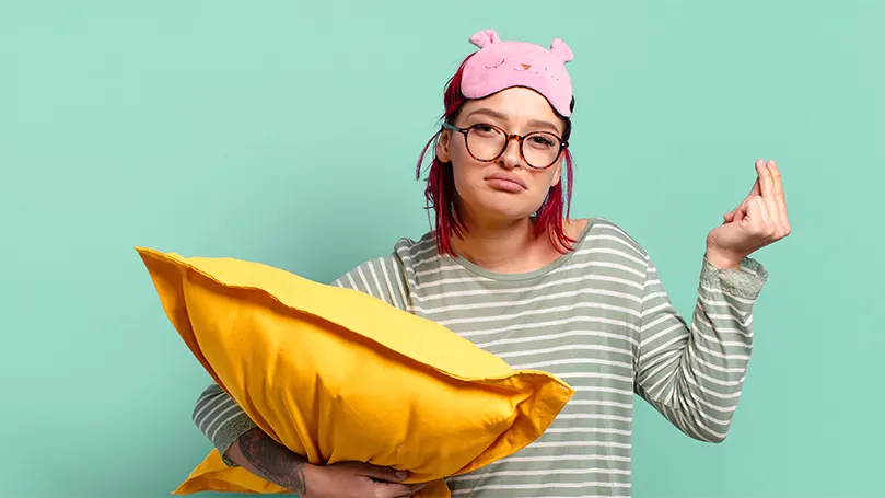 An image of a sleepy woman holding a pillow.