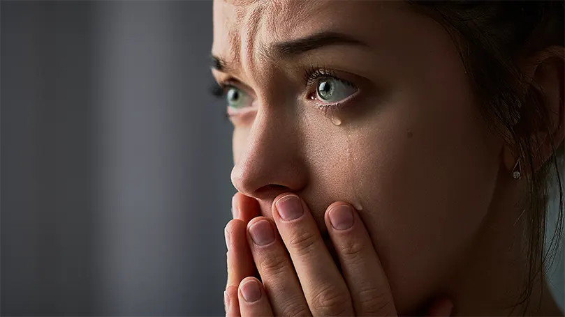 An image of a sad woman with green eyes crying.