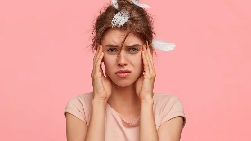 An image of a woman who hasn't gotten sufficient sleep looking unhappy