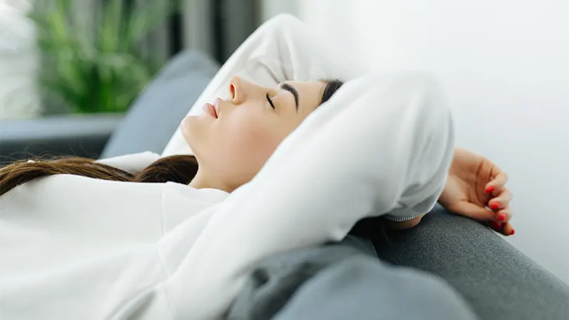 A woman relaxing in her bed with her hands behind her head