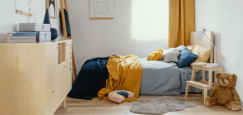 Bedroom with wooden bed with navy blue and yellow soft furnishings.