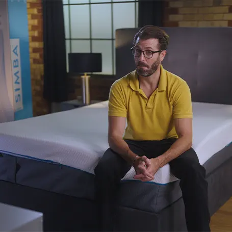 An image of a TSA reviewer sitting on a Simba Hybrid Luxe mattress